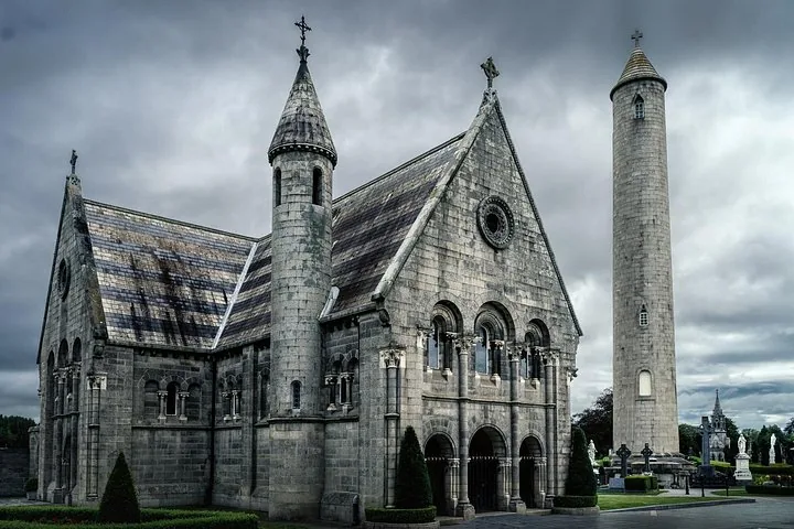 Large stone church building and tall round tower in a cemetery